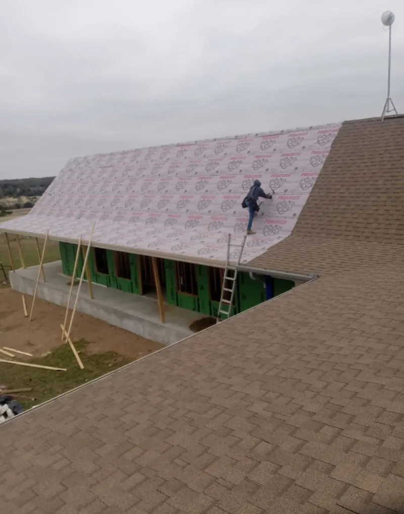 Worker preparing underlayment for a metal roof installation in Pierre